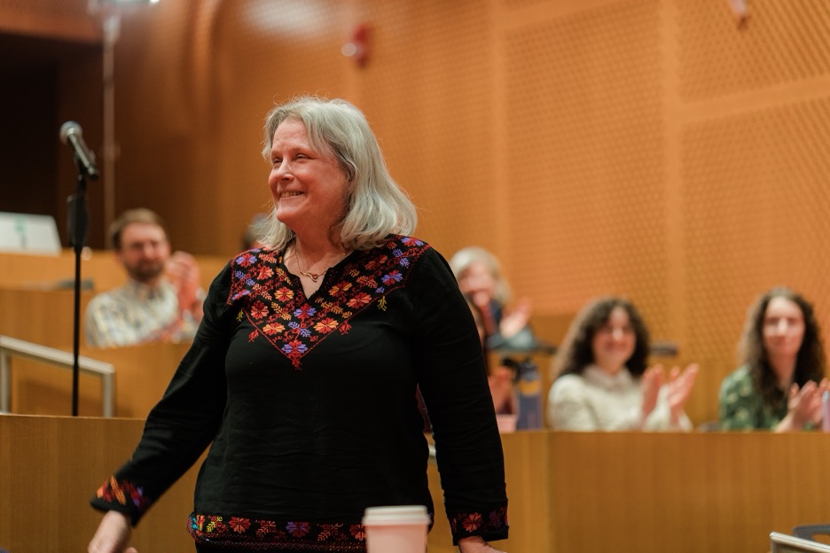Barbara Hughey smiling as event attendees give her a round of applause.