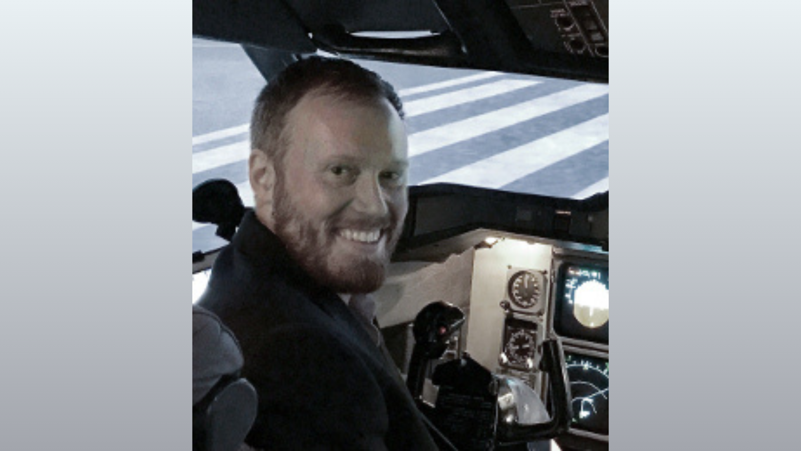 John Thomas smiling as he sits in what appears to be an aircraft.