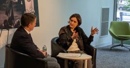 Candid photo of a woman in business casual attire speaking animatedly to a man during a panel.