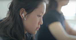 Student working at laptop wearing AirPods