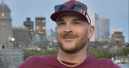 Joshua Gayman smiling wearing a maroon MIT baseball hat