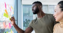 two people writing on sticky notes