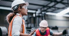Young woman wearing hardhat and reflective vest in a factory. "Webinar: Inside the Principles of Manufacturing MicroMasters® Program"