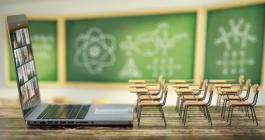 Giant laptop open in front of miniature desks