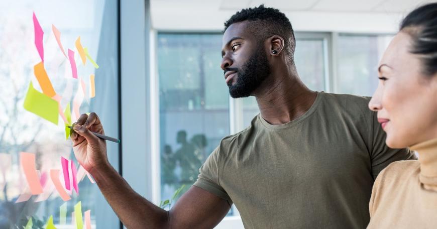 two people writing on sticky notes