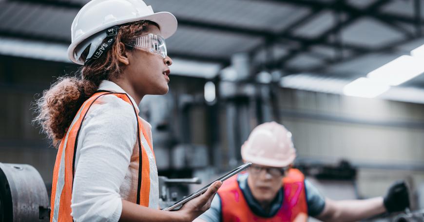 Young woman wearing hardhat and reflective vest in a factory. "Webinar: Inside the Principles of Manufacturing MicroMasters® Program"