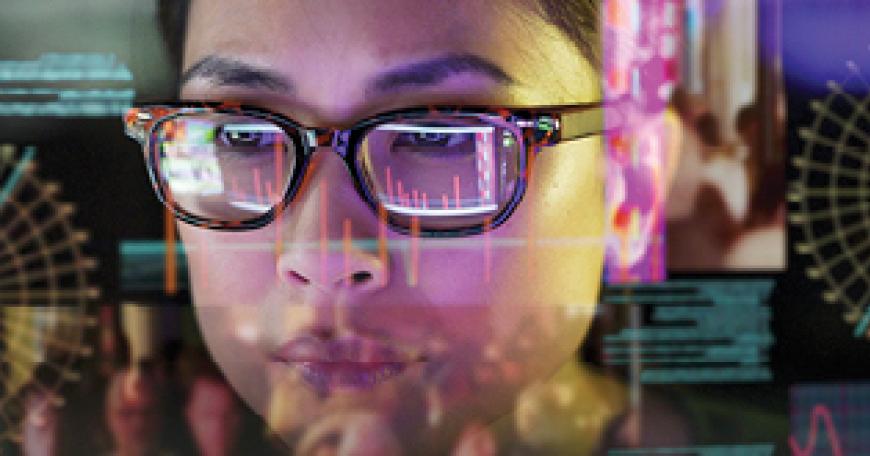 View of a woman's face as if seen from behind a computer screen, with charts and apps reflected across her face