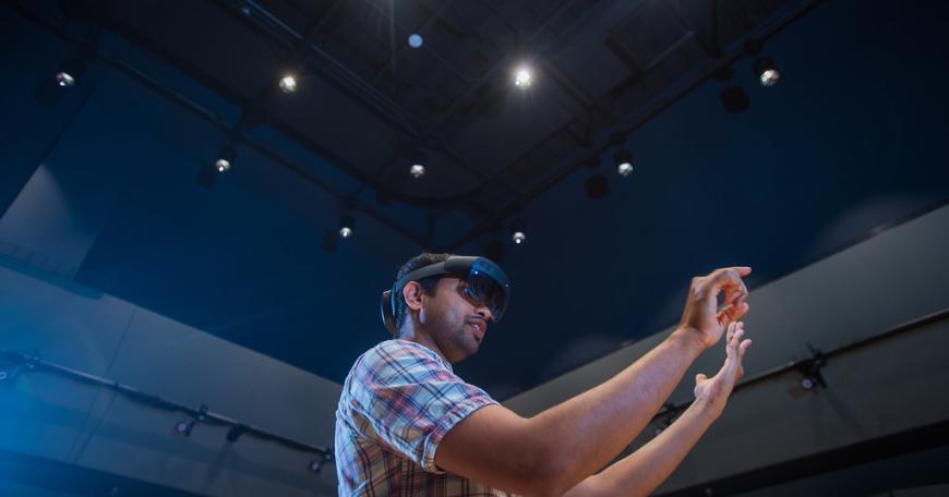 Photo of a man wearing a VR headset and holding out his arms.