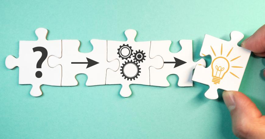 4 connecting puzzle pieces. First piece has a question mark, second piece has an arrow, third piece has gears, fourth piece has another arrow. Fifth puzzle piece with lightbulb on it is about to connect with the others.