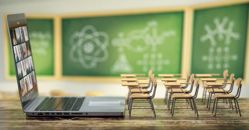 Giant laptop open in front of miniature desks