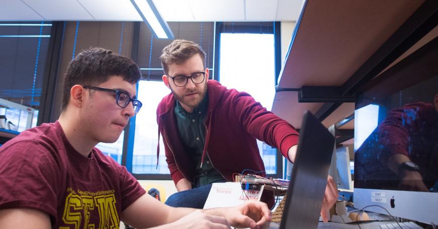 Senior lecturer Joe Steinmeyer (standing) assists a student in 6.08, (Introduction to EECS via Interconnected Embedded Systems).