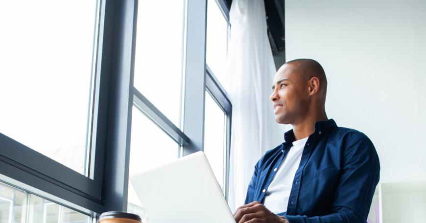 A man working on a laptop looks out the window