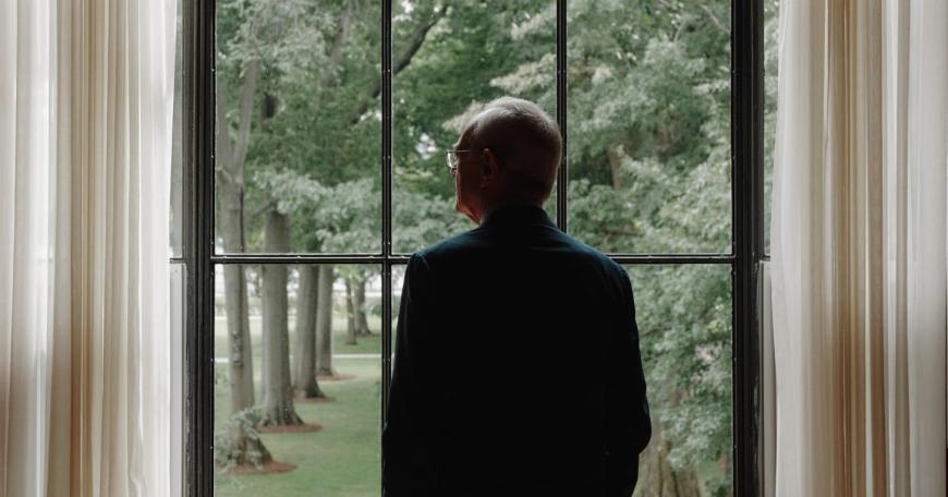 Photo of a man wearing a suit looking out a window