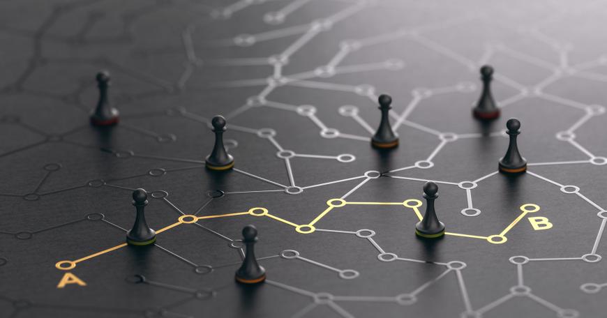 Photo of pawn chess pieces on a table with drawings of lines connecting nodes.