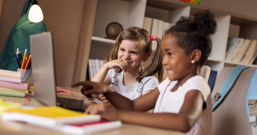 Two little girls playing at a laptop computer