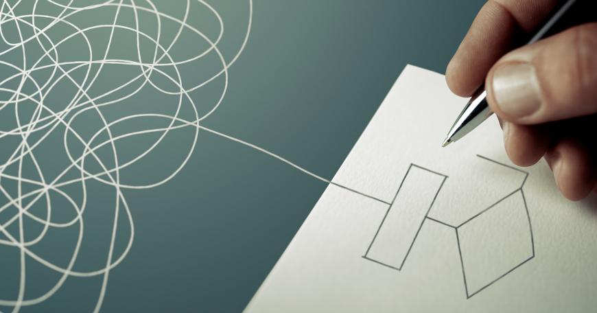 A tangle of string overlaps with a piece of paper where it turns into a drawing of a straight line, a rectangle, and a diamond. A hand holds a pen over the paper. 