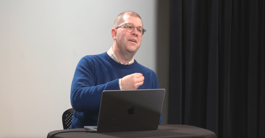 Headshot of Devin Caughey talking and sitting behind a laptop
