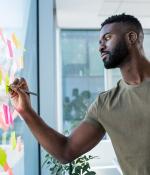 two people writing on sticky notes
