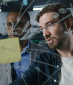 two people writing on a board