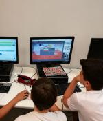 Three middle school-aged male students seated at two computers, rear view