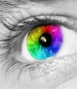 Black and white close up of an eye, with the iris in rainbow colors