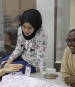 At left, an illustration of a network surrounded by the words "entrepreneurship academic employment networks." At right, a photo of a woman in hijab talking with two friends just offscreen.