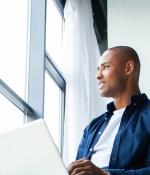 A man working on a laptop looks out the window