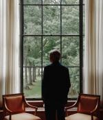 Photo of a man wearing a suit looking out a window