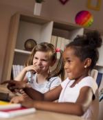 Two little girls playing at a laptop computer